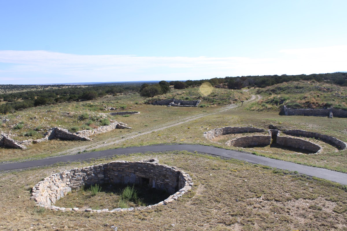 A paved path winds through the stone foundations of several old kivas. 
