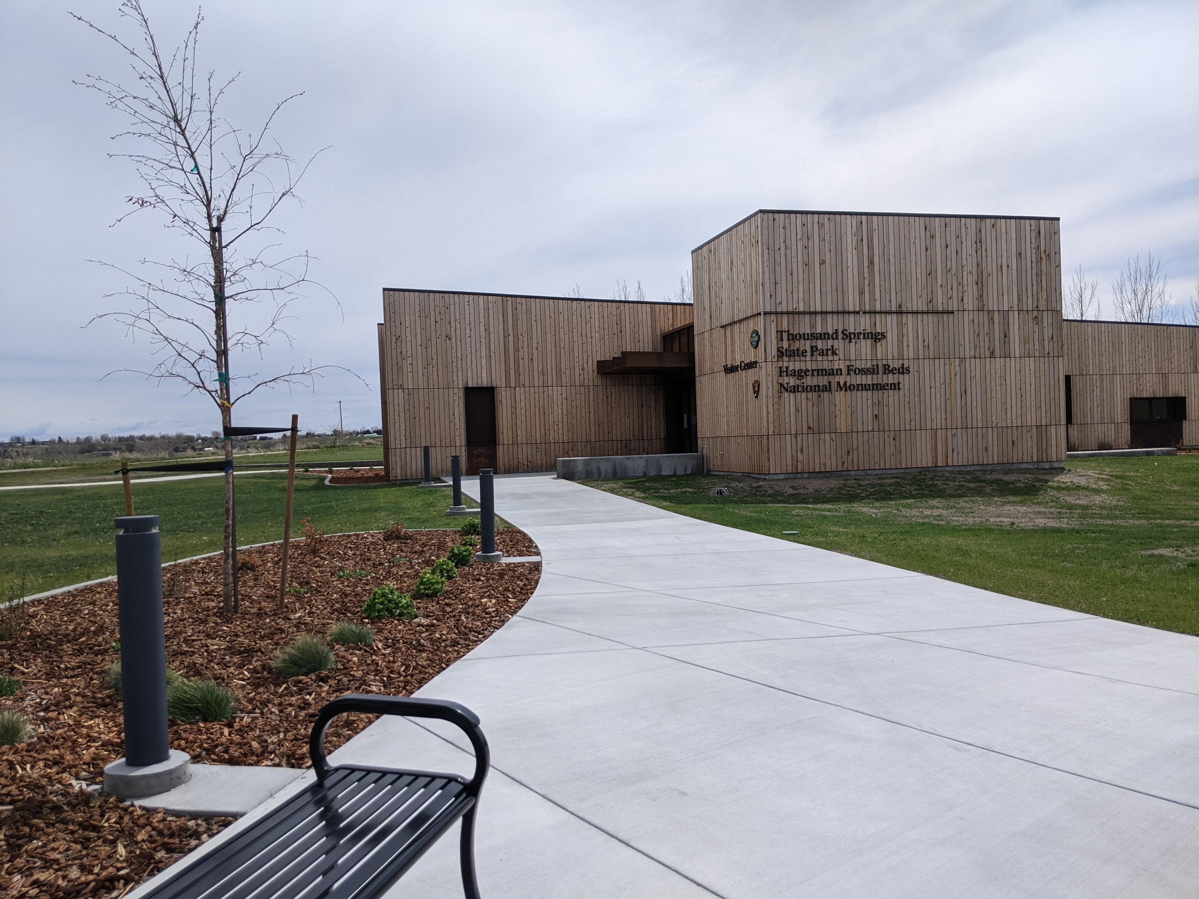 A sidewalk leads to a boxy, wood-paneled building labelled as 