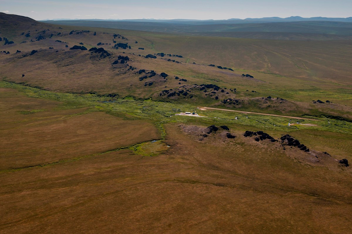 A vast expanse of undulating hills with granite spire jutting from the top. 