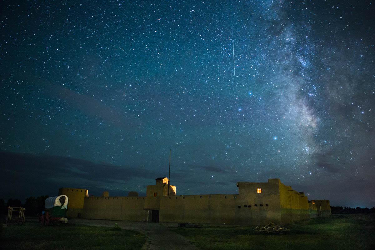 An adobe fort with lights under a starry sky