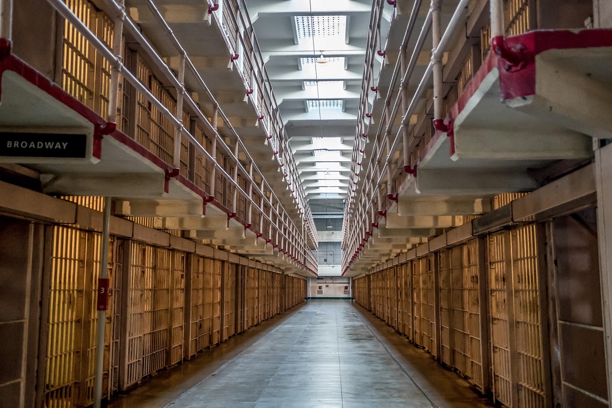 A corridor extends between two rows and three tiers of cells. Skylights let in light from overhead. 