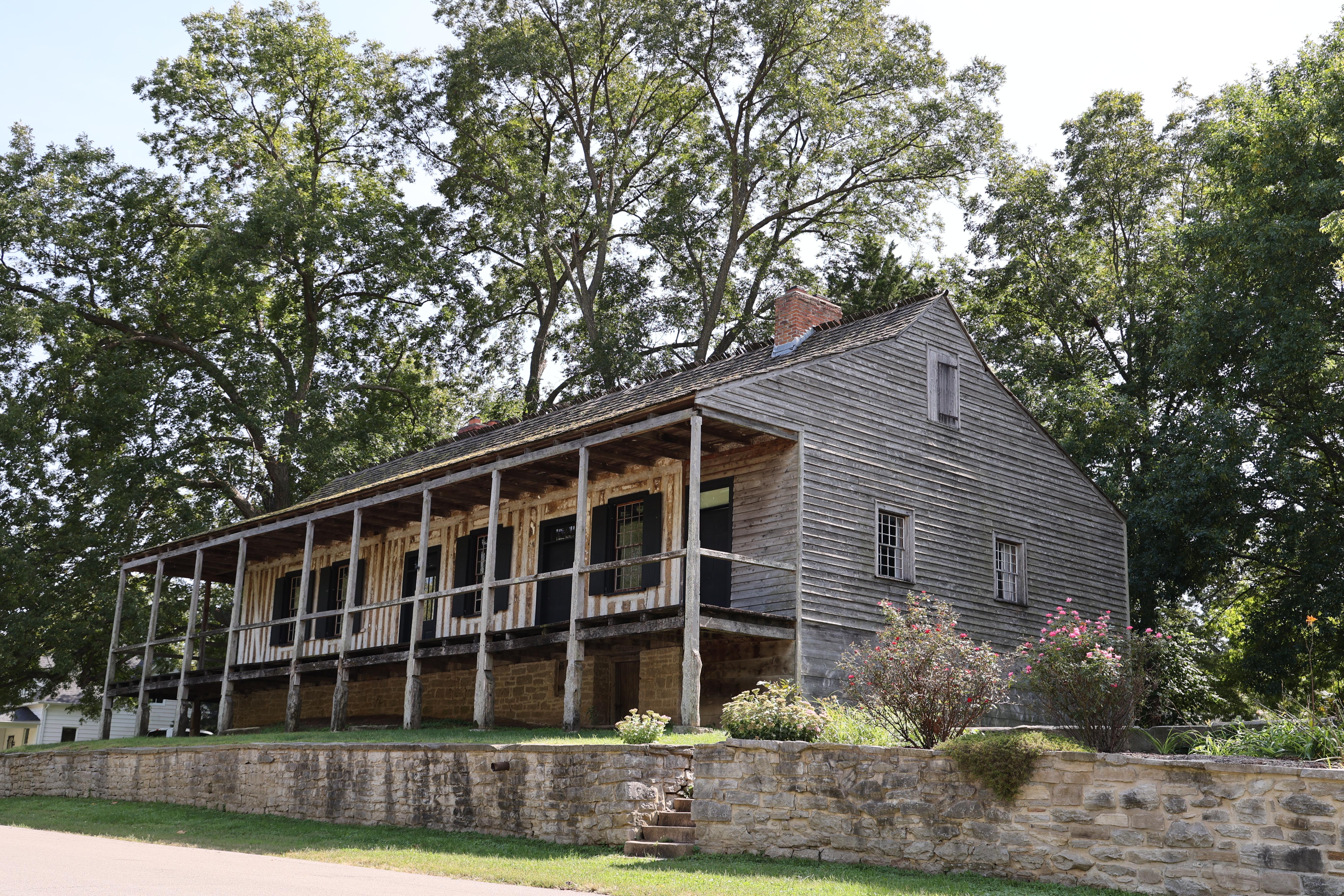 A large raised building with a covered porch and vertical log construction visible.