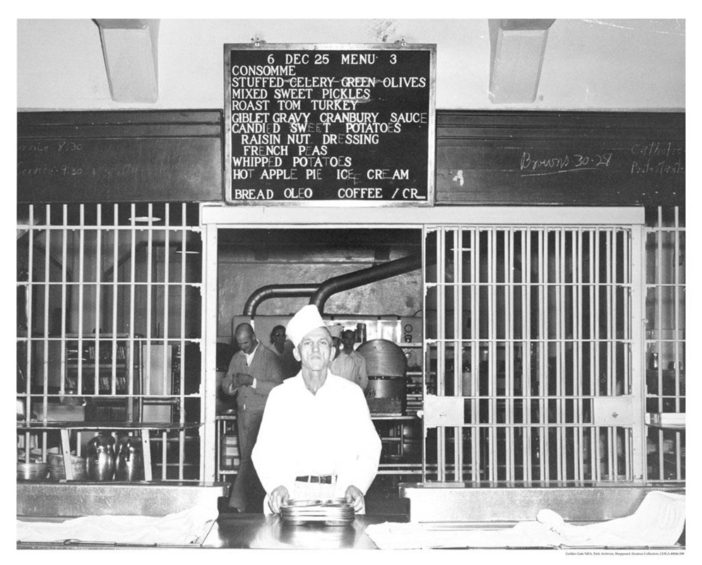 Cook serving Christmas dinner with menu posted above.