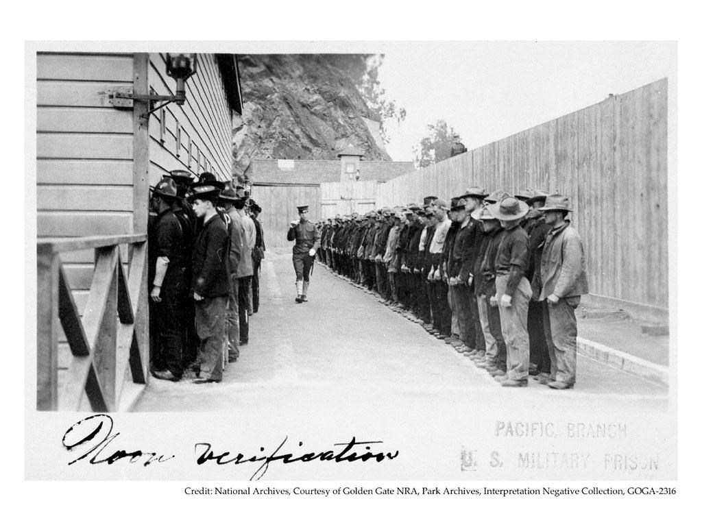 A military officer walks between two long lines of roughly dressed men