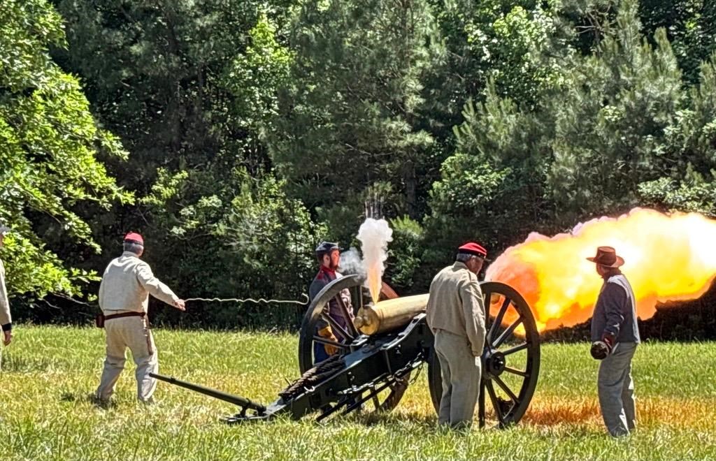 Five men in Confederate uniforms fire a cannon.