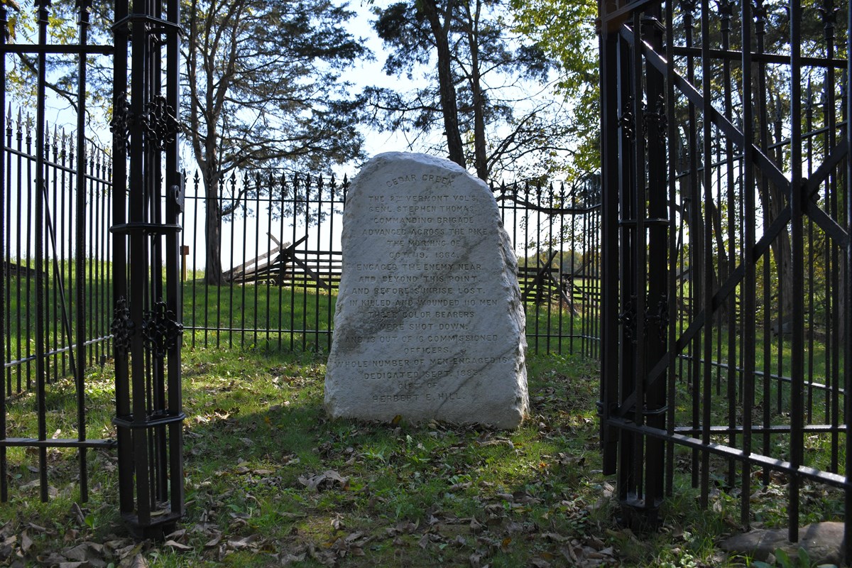 A rough marble monument in an iron-fenced enclosure commemorates Civil War combat.