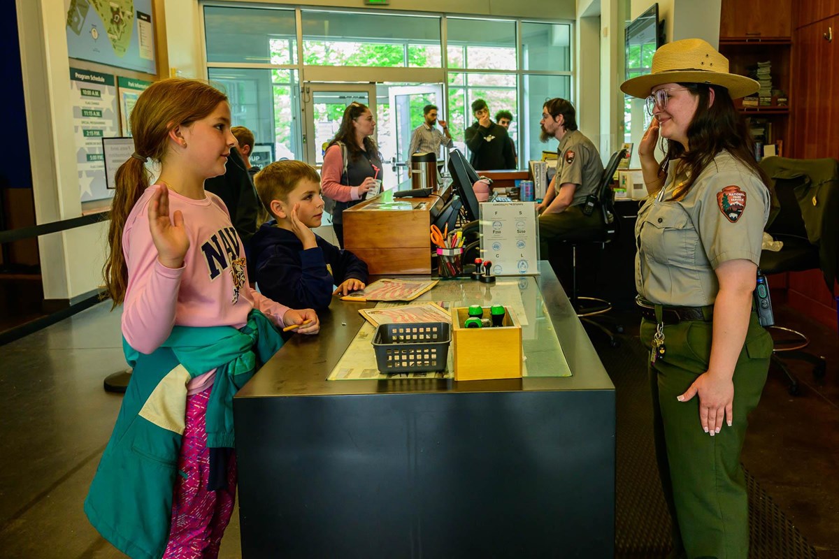 Two young visitors with their right hands in the air as they are sworn in as Junior Rangers