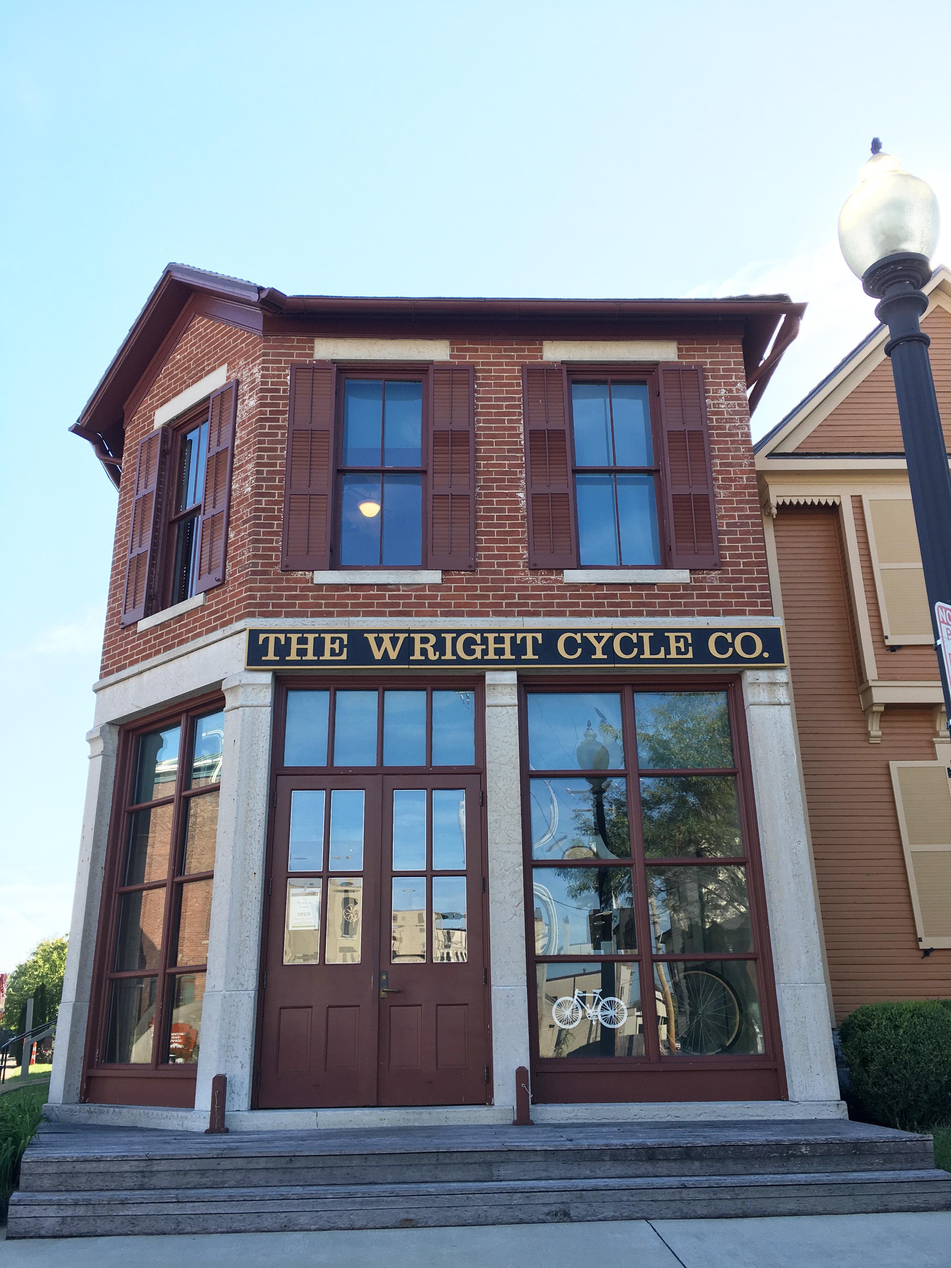 A two-story brick building with tall windows and shutters on them with sign 