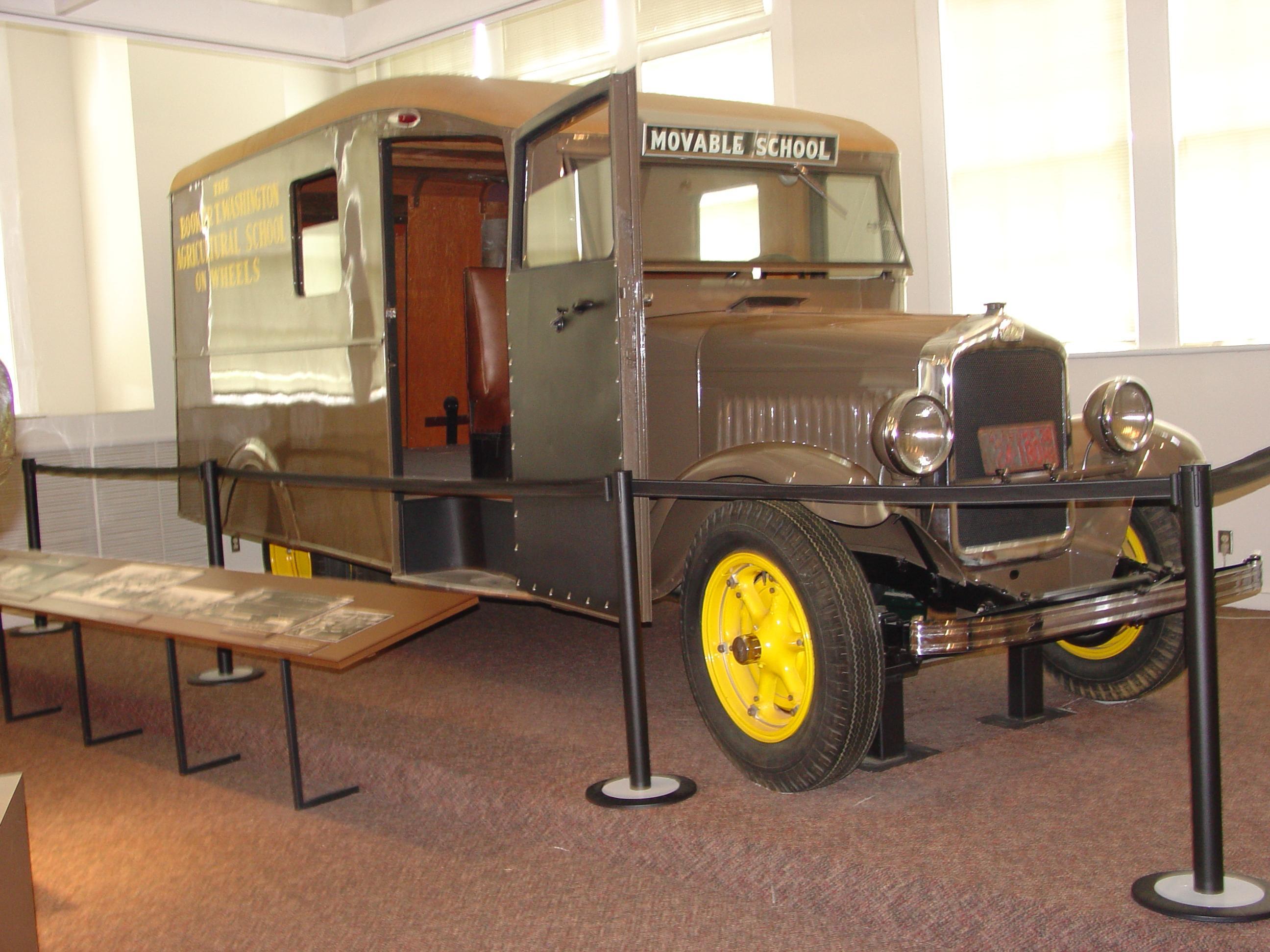 A  brown colored modified school bus with two windows