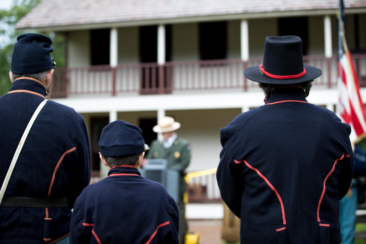 Photo of Union Union artilleryman reenactors standing in front of building. 