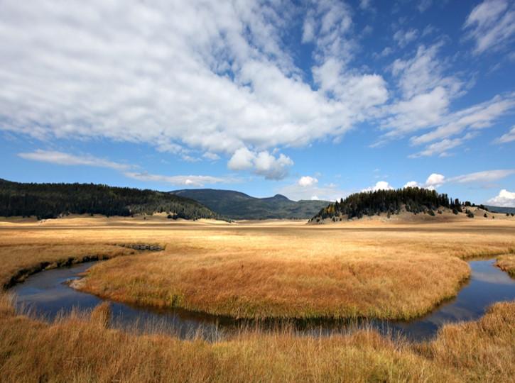 Scattered clouds over landscape view of winding river and brown grasslands