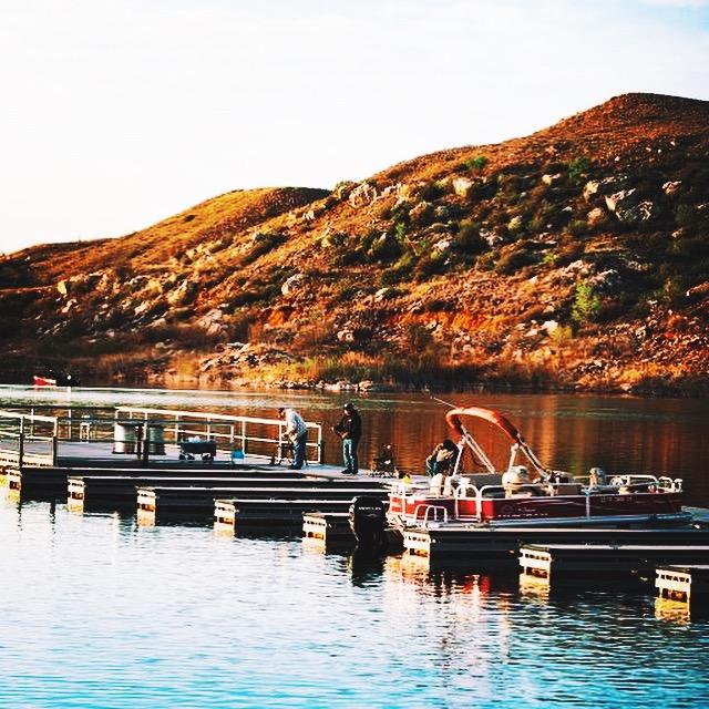 Sanford Yake boat docks.  The water is blue and calm.  There are a few fisherman fishing.