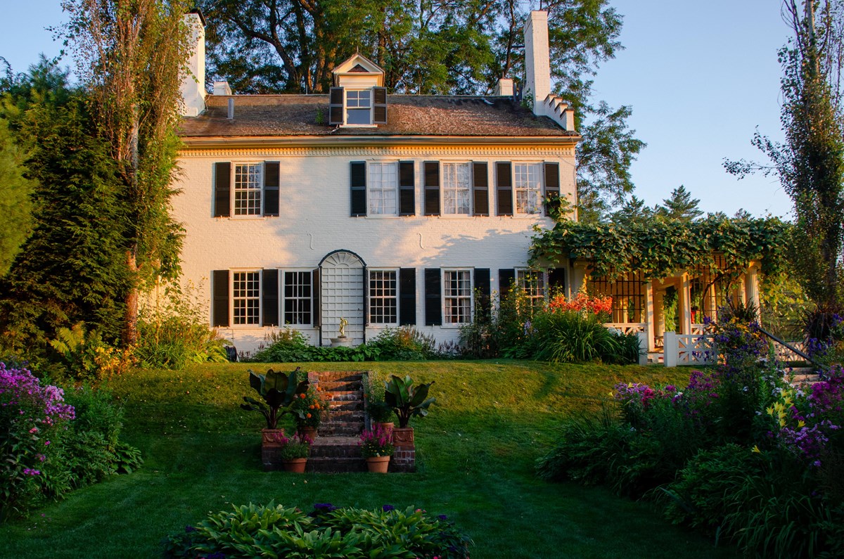 historic white brick house with flower gardens