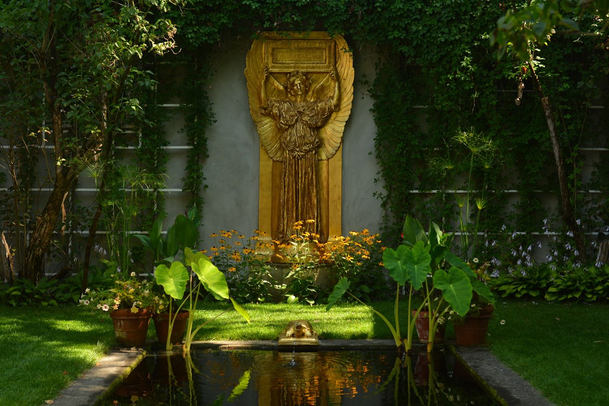 gilded statue of angel with plants and reflecting pool