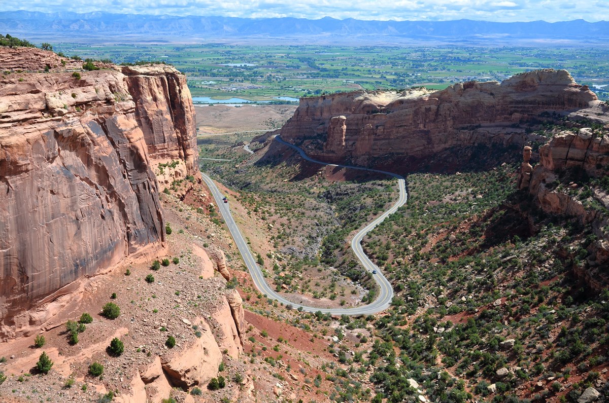 Looking down from canyon rim at a U shaped portion of road entering and exiting the canyon