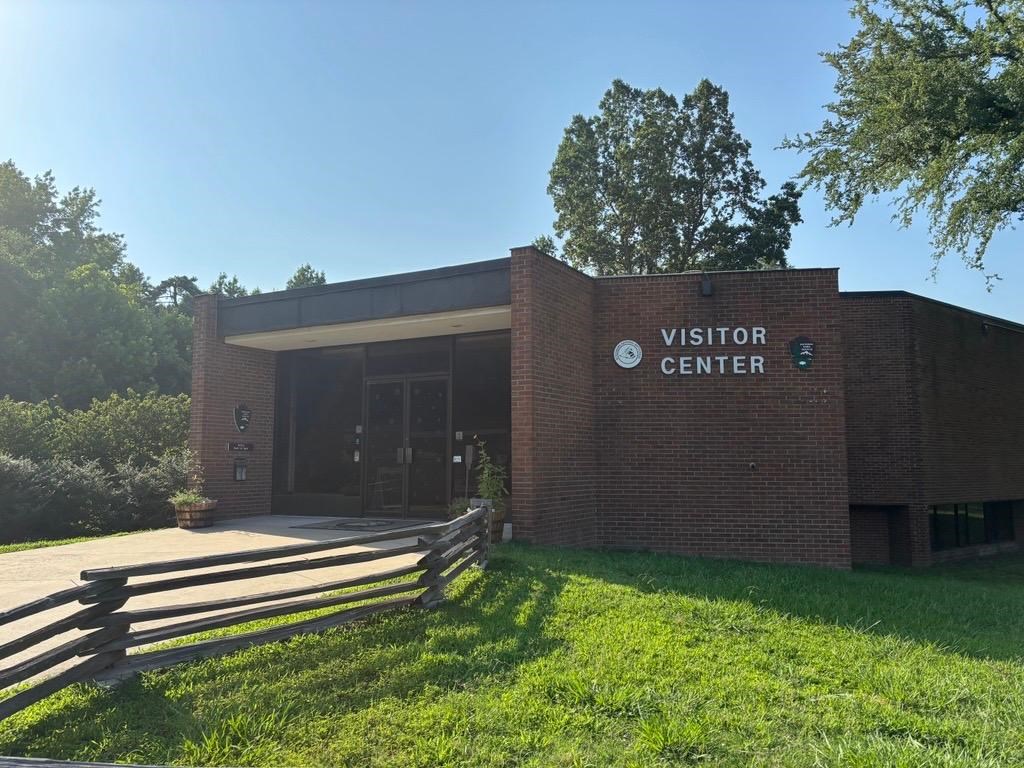 Pictured is the front of the brick visitor center under a cloudless blue sky.