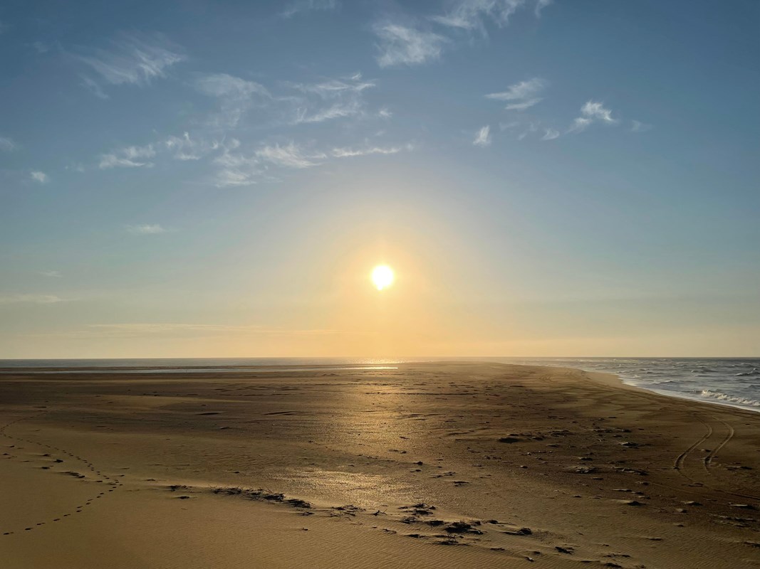 a yellow glow of the risiing sun over the beach and ocean