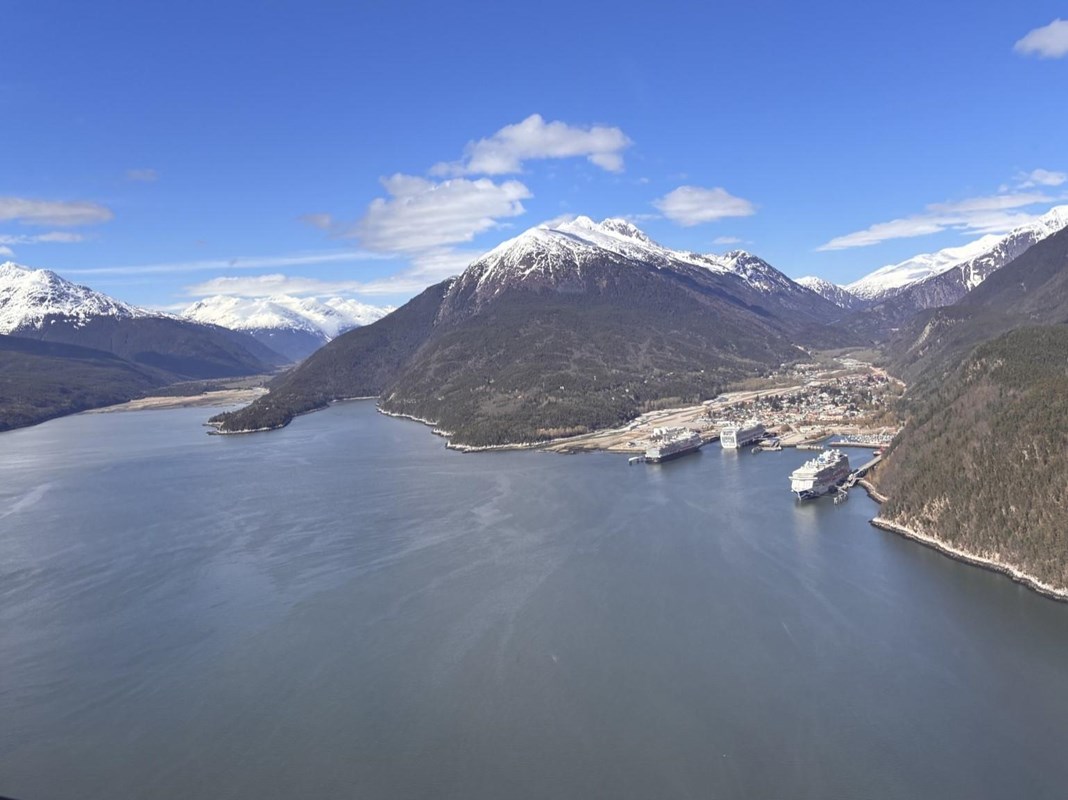Aerial image of two inlets in a deep fjord, with a small city and large cruise ships tucked in one