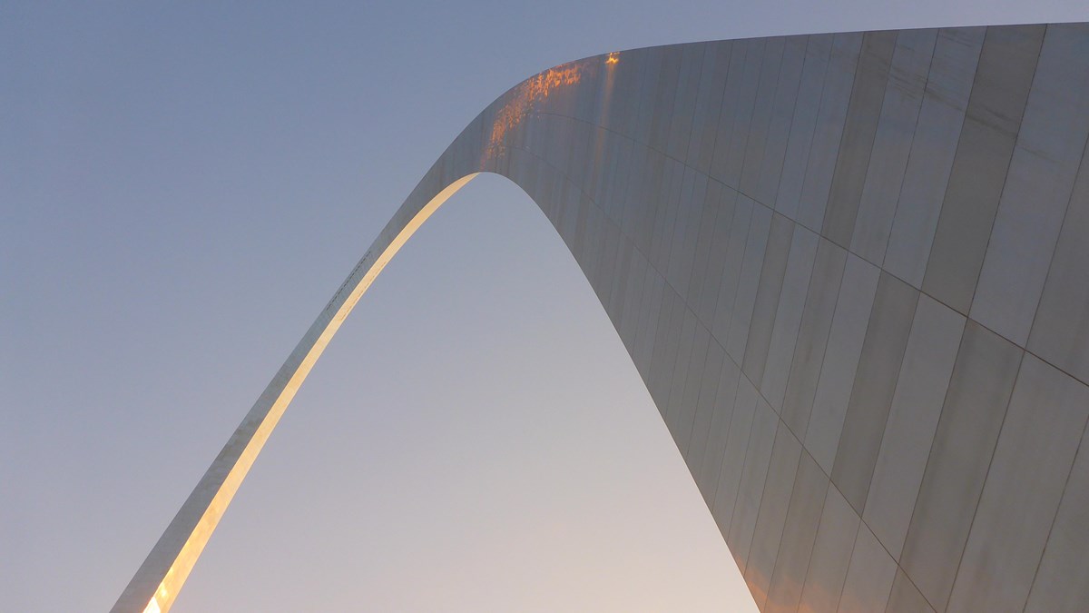 looking up at the curve of the Gateway Arch against the sky