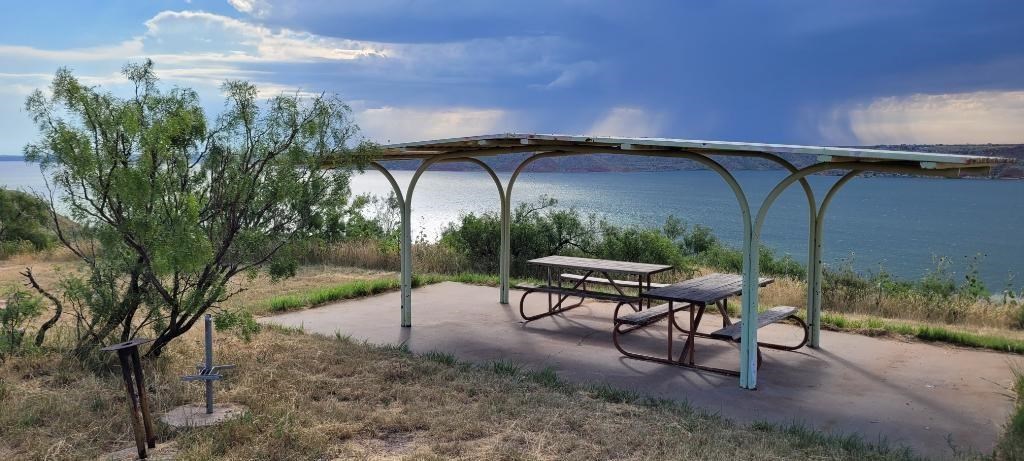Picnic shelter at a campsite overlooking Lake Meredith.  The sky is blue with no clouds. 