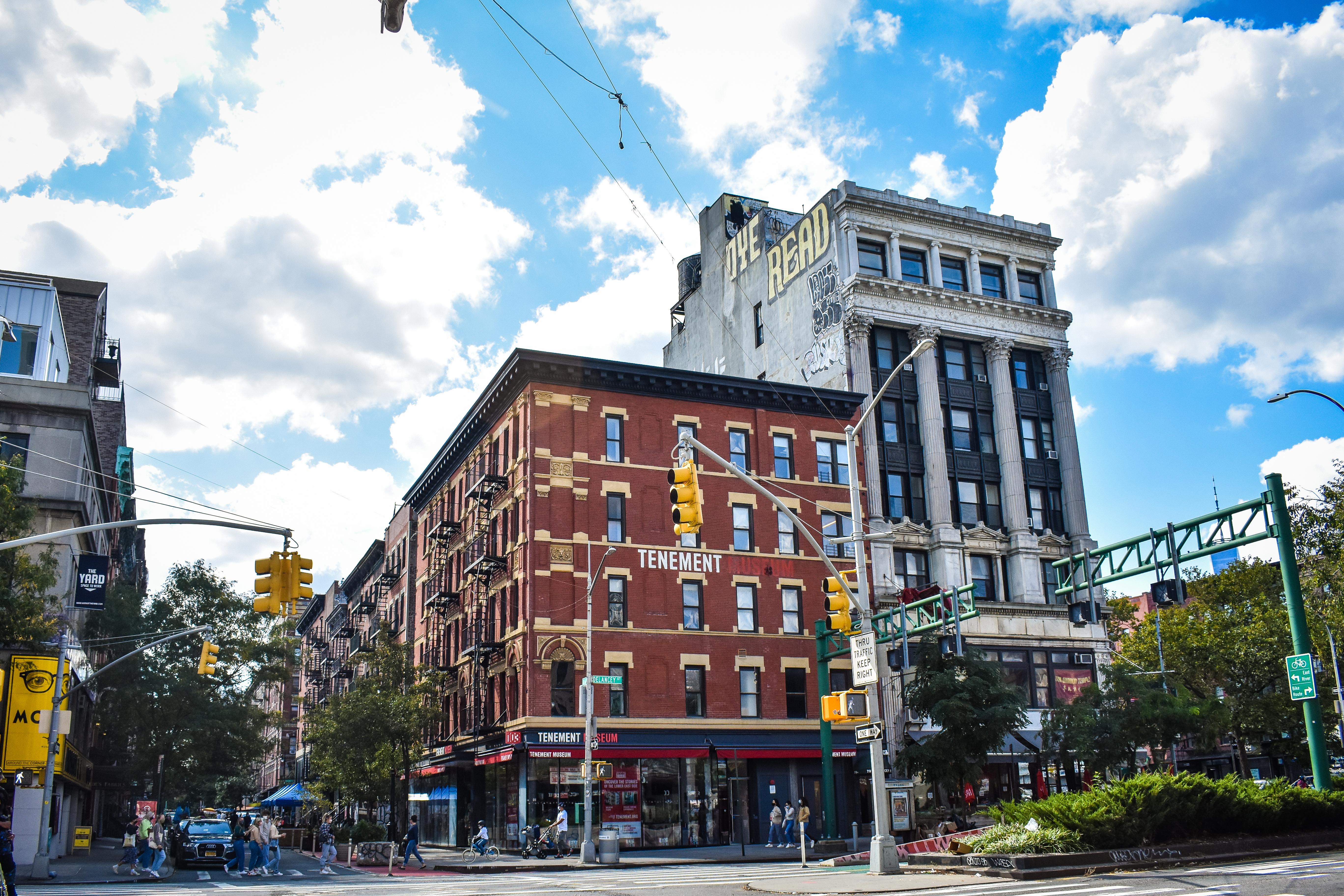 A four story red brick building against a blue sky with white puffy clouds