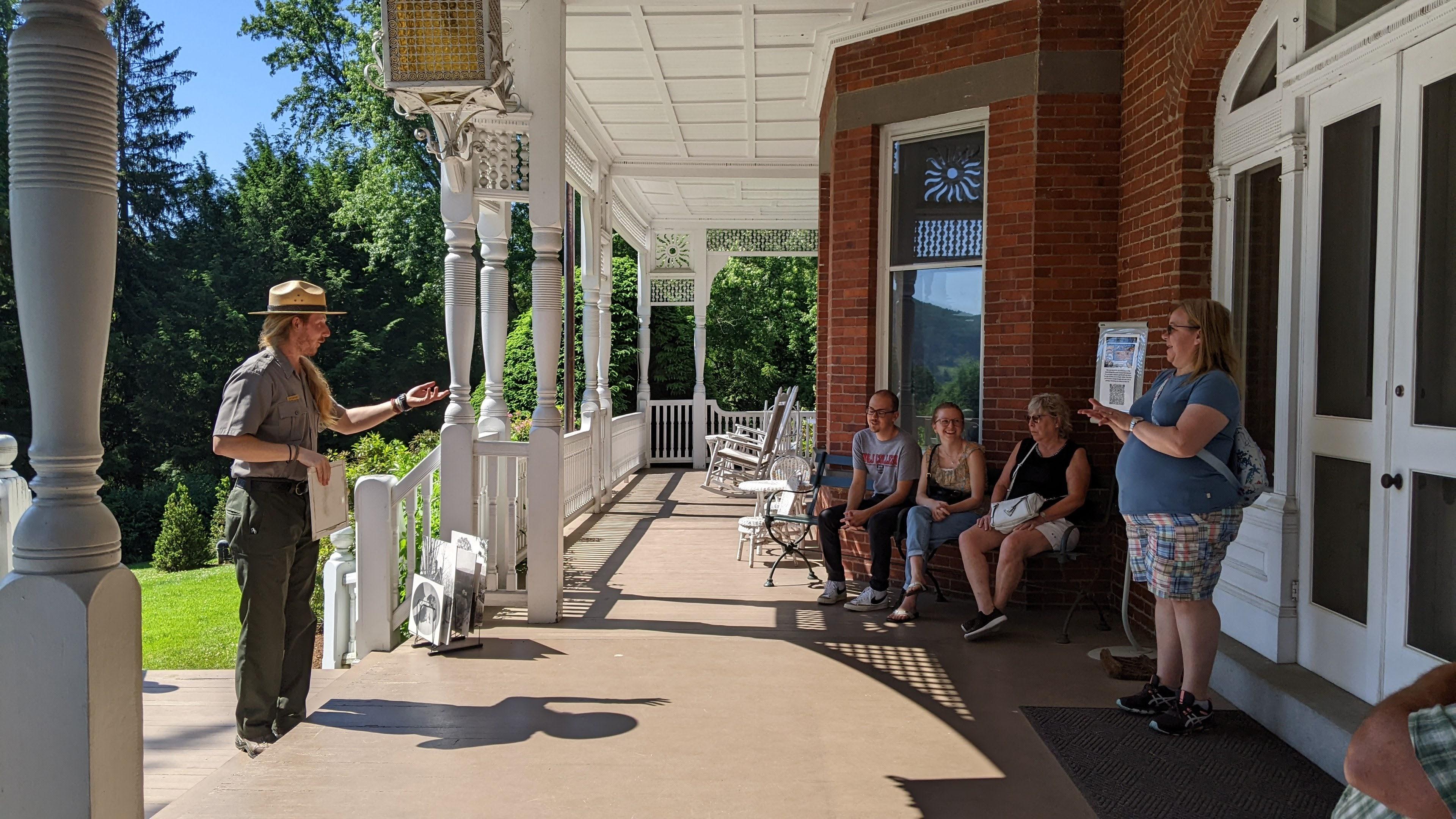 Park Ranger talks to group of park visitors on the porch of the Marsh-Billlings-Rockefeller mansion