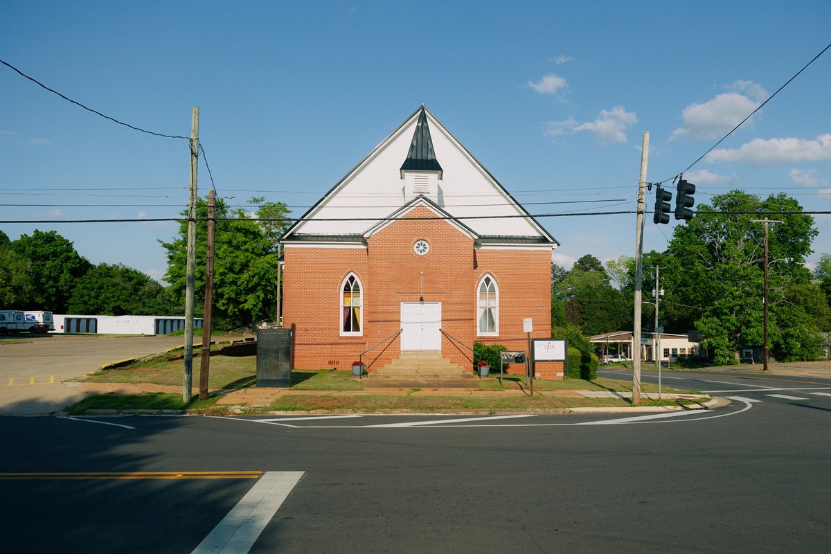 A small brick building with a pitched roof, blue sky in the background.