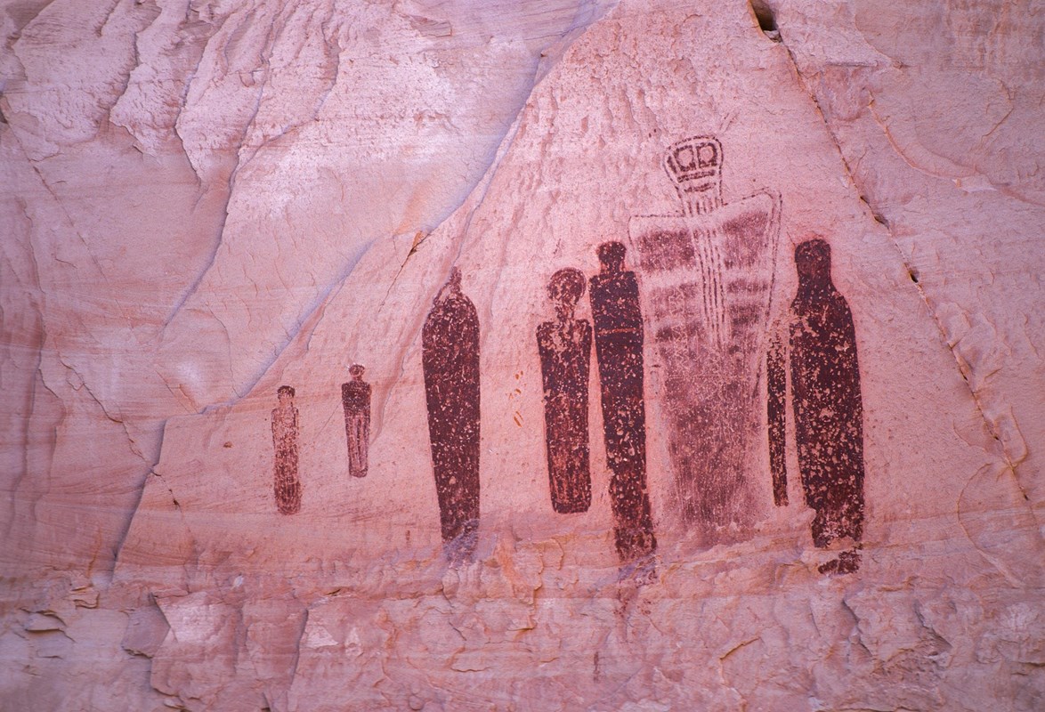 Large reddish pictographs on a lighter red sandstone wall