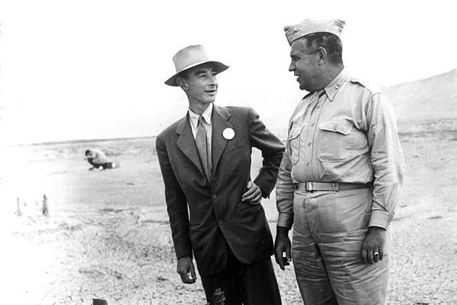 Historic photo of two men standing next to a mangled piece of metal equipment in the desert.