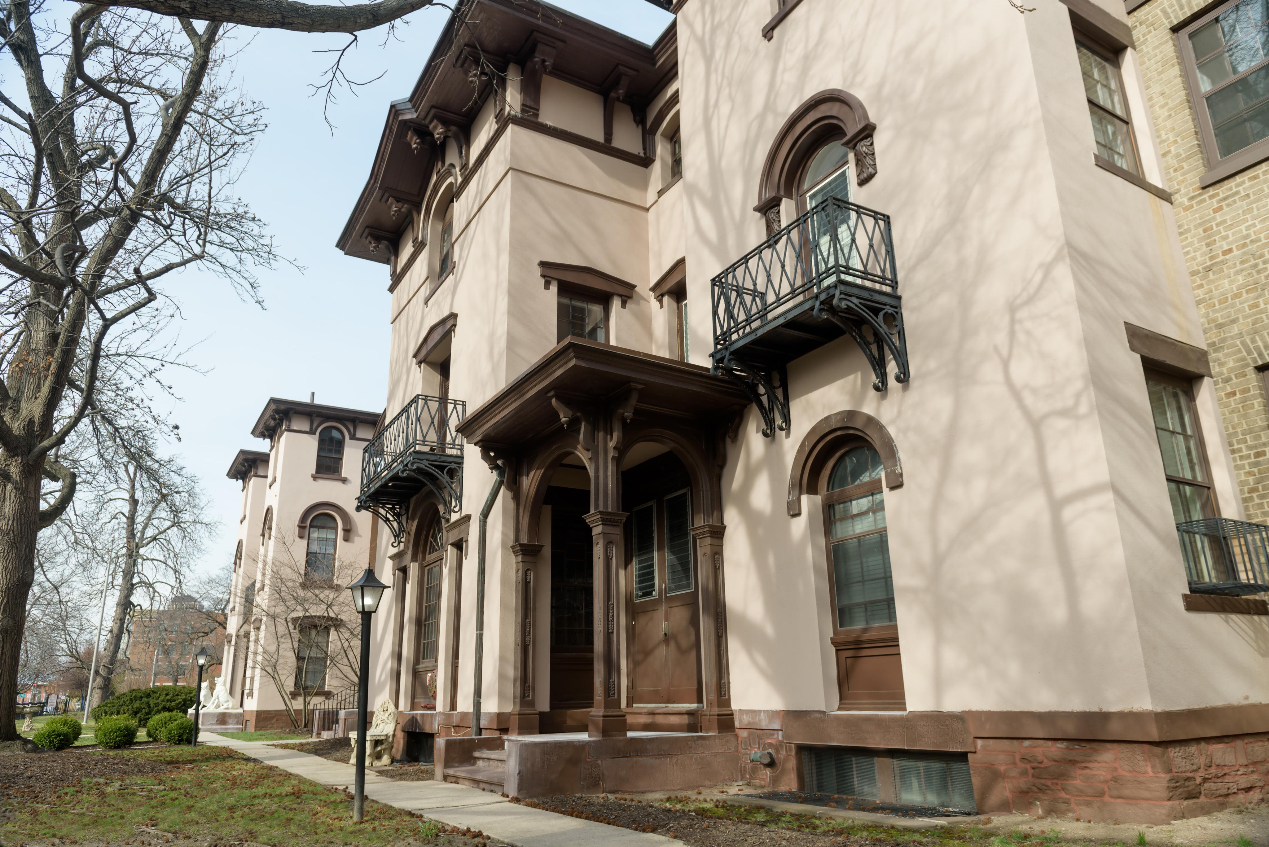 A tan and brown building, built in the Italian Villa style with rounded arches and balconies.