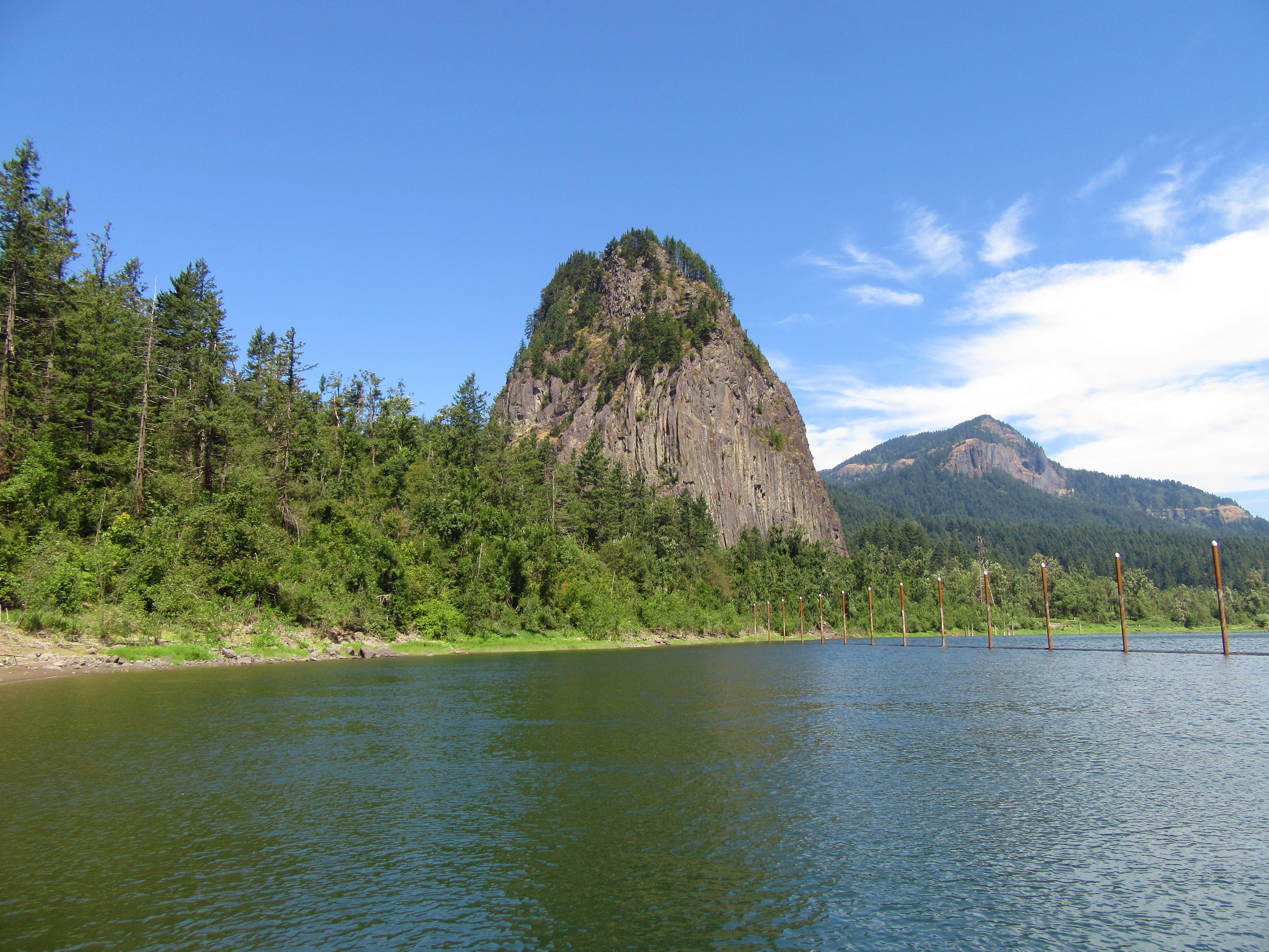 Water in the foreground with large conical rock on shore