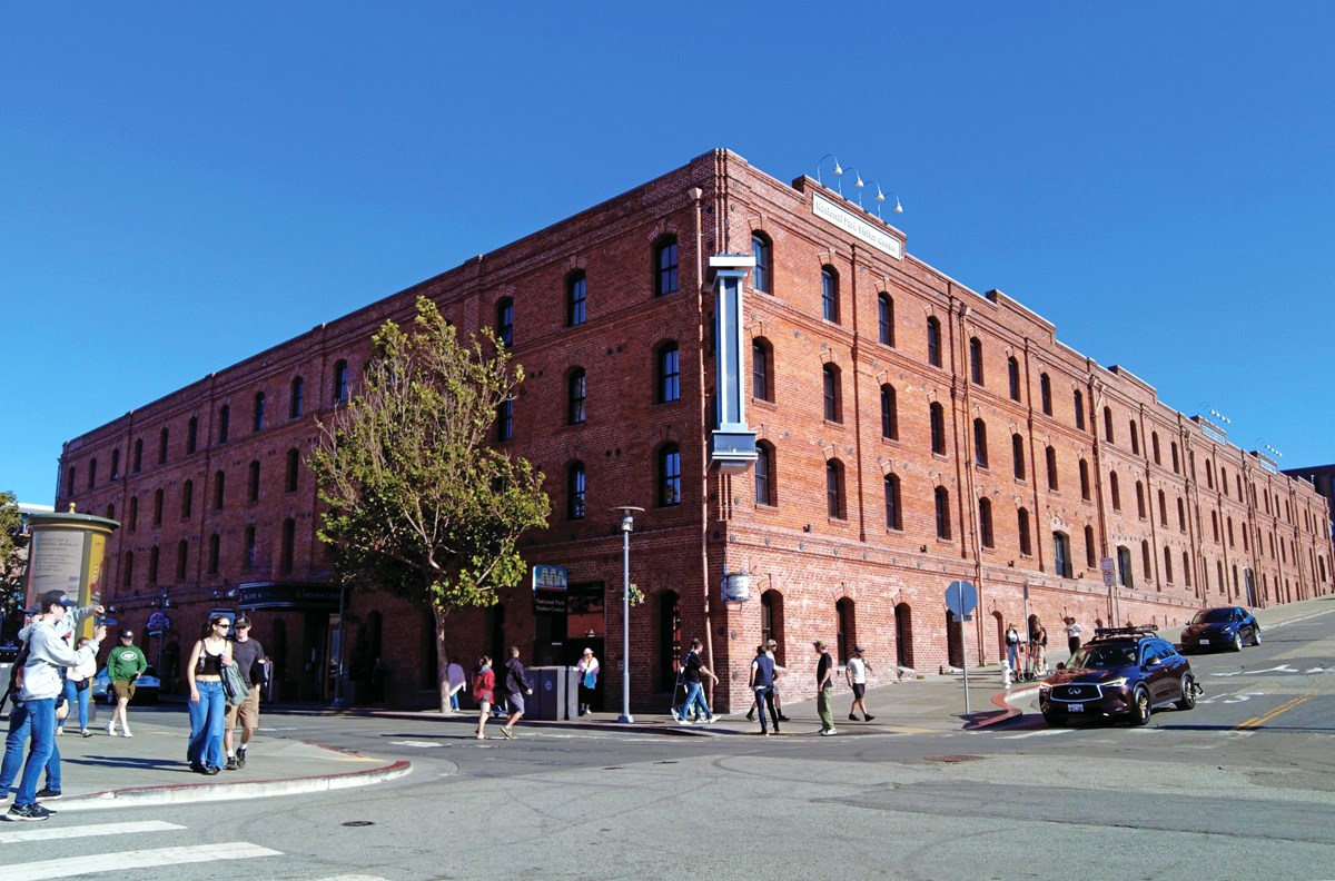 a historic brick building stands on the corner of a busy street.