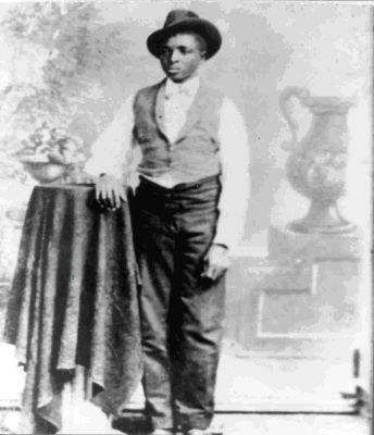 A young teenage boy standing with his hand on a table, looking to the right