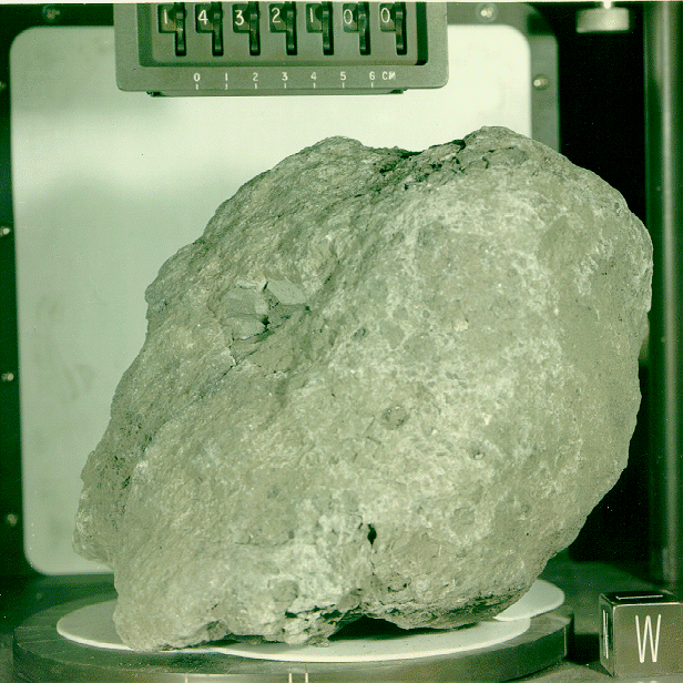 Black and white photo of a gray rock about 23 centimeters in diameter with a centimeter scale next to it labeled "1432100"
