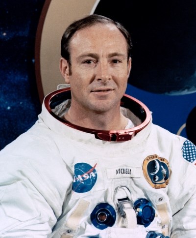 a man wearing a white spacesuit with several patches on it including the NASA emblem