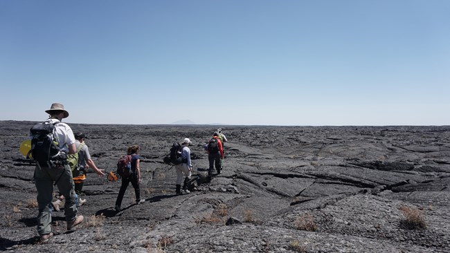 scientists hiking on lava