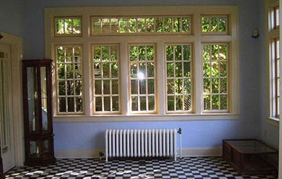 Room with blue walls, multi-light wood windows, and a radiator beneath the windows.