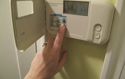 Hand setting the controls on a programmable thermostat.