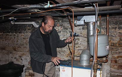 Man using hand-held equipment to test the performance of a furnace.