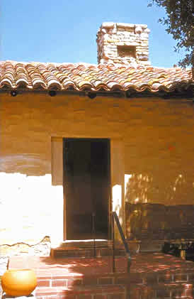 This is an image of a small house with adobe walls, stone chimney, and tile roof and steps. It has a single, rectangular doorway, somewhat recessed. The image rolls over to provide the correct answer. Screen Reader users see text-only link, left, for answer. Photo: NPS files.
