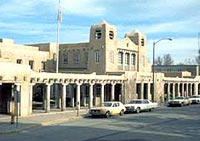 This is an image of an long adobe building with twin towers, a parapet, and various blocks of different sizes. Its primary character-defining feature is the arcade that comprises the building's facade. Photo: NPS files.
