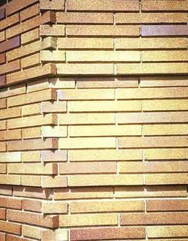This is an image of a brick wall. The unusually long bricks in varying shades of yellow-brown are distinctive, but the related craft details are perhaps more important in establishing the visual character. Every ninth course, there is a row of recessed bricks that creates a shadow pattern on the wall; the deeply recessed mortar joints that create a secondary pattern of shadows; and a there is 'toothed' effect, where the bricks overlap each other at the corner of the building. Photo: NPS files.