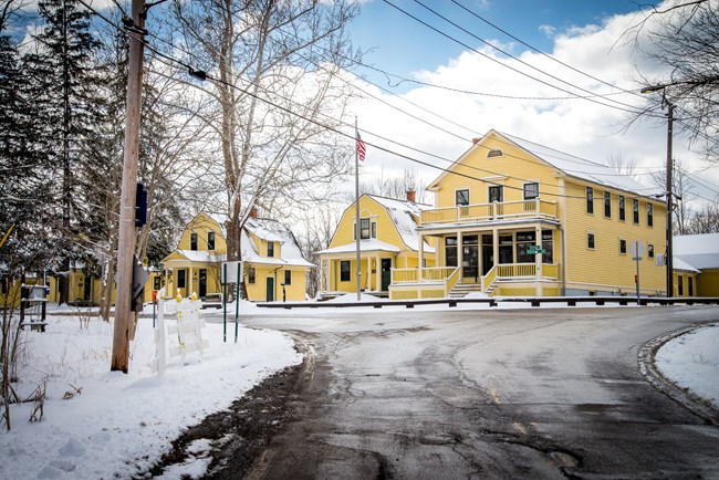 HQ in winter A row of yellow cottages at a road intersection, with snow on the ground.