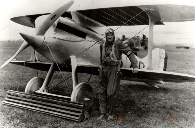 Black and white image of Captain Burt Skeel standing in front of his Army Curtiss R-8 Racer (airplane).