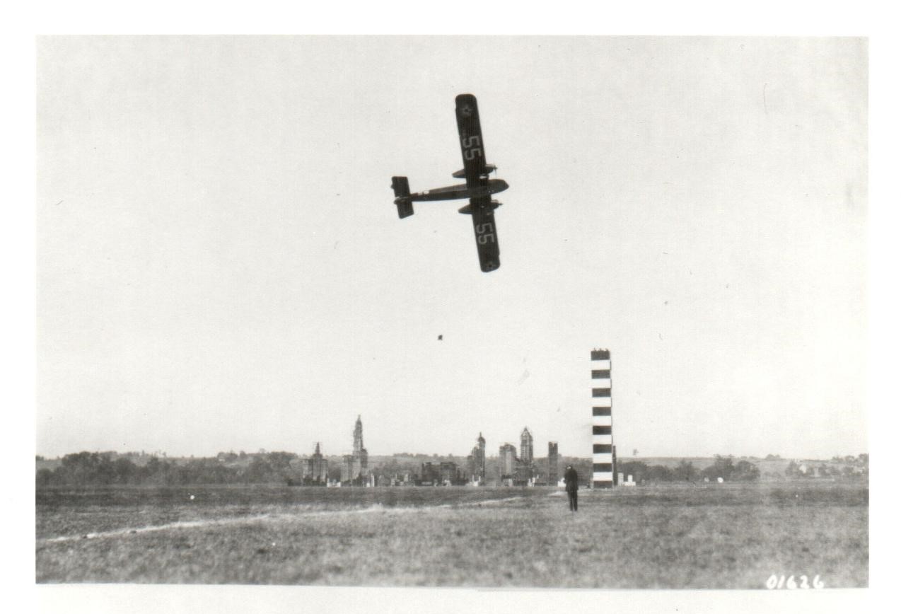 Black and white image of an aeromarine plane in flight above a striped pylon.