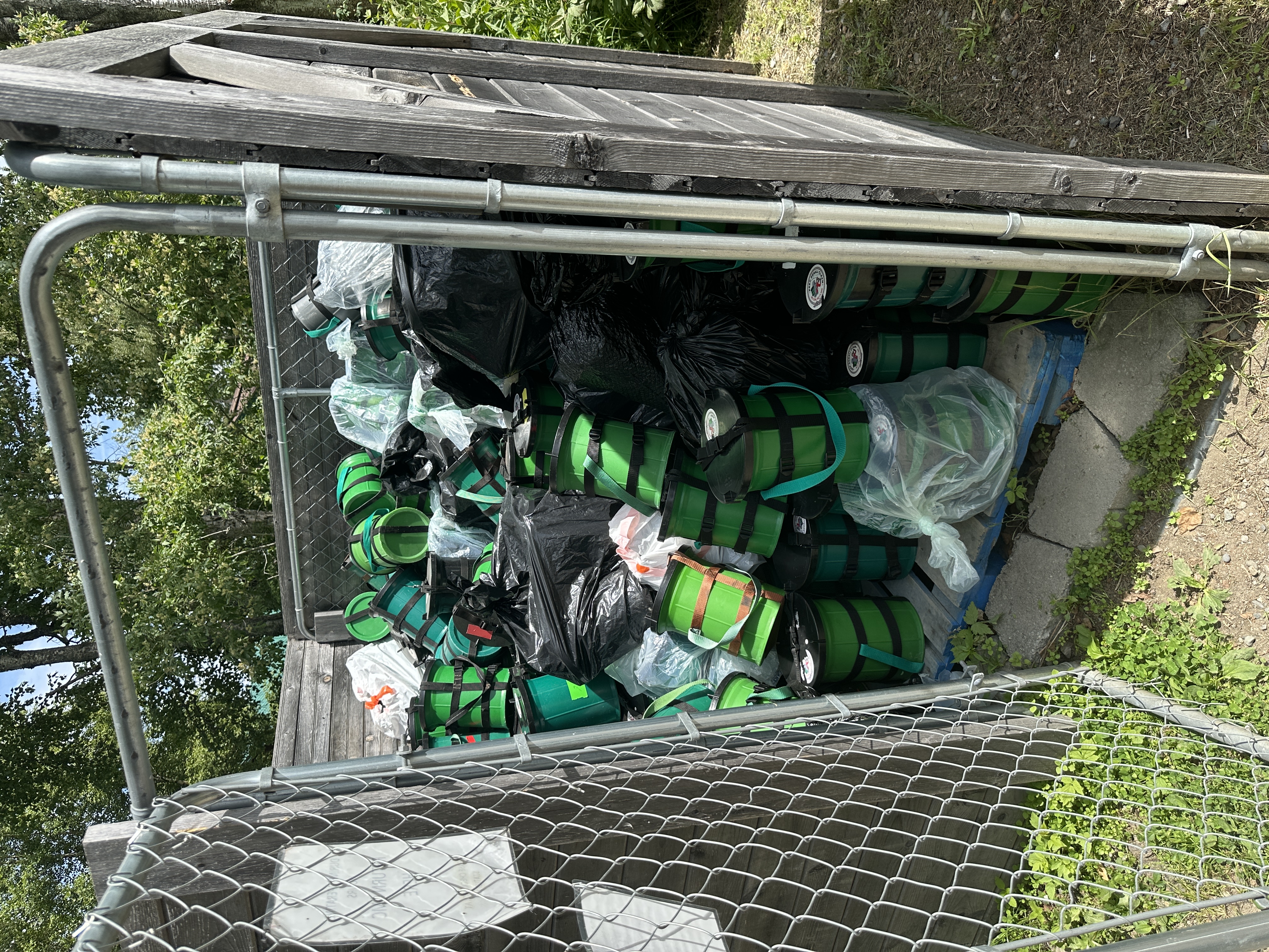 A chainlink enclosure full of green and black cannisters