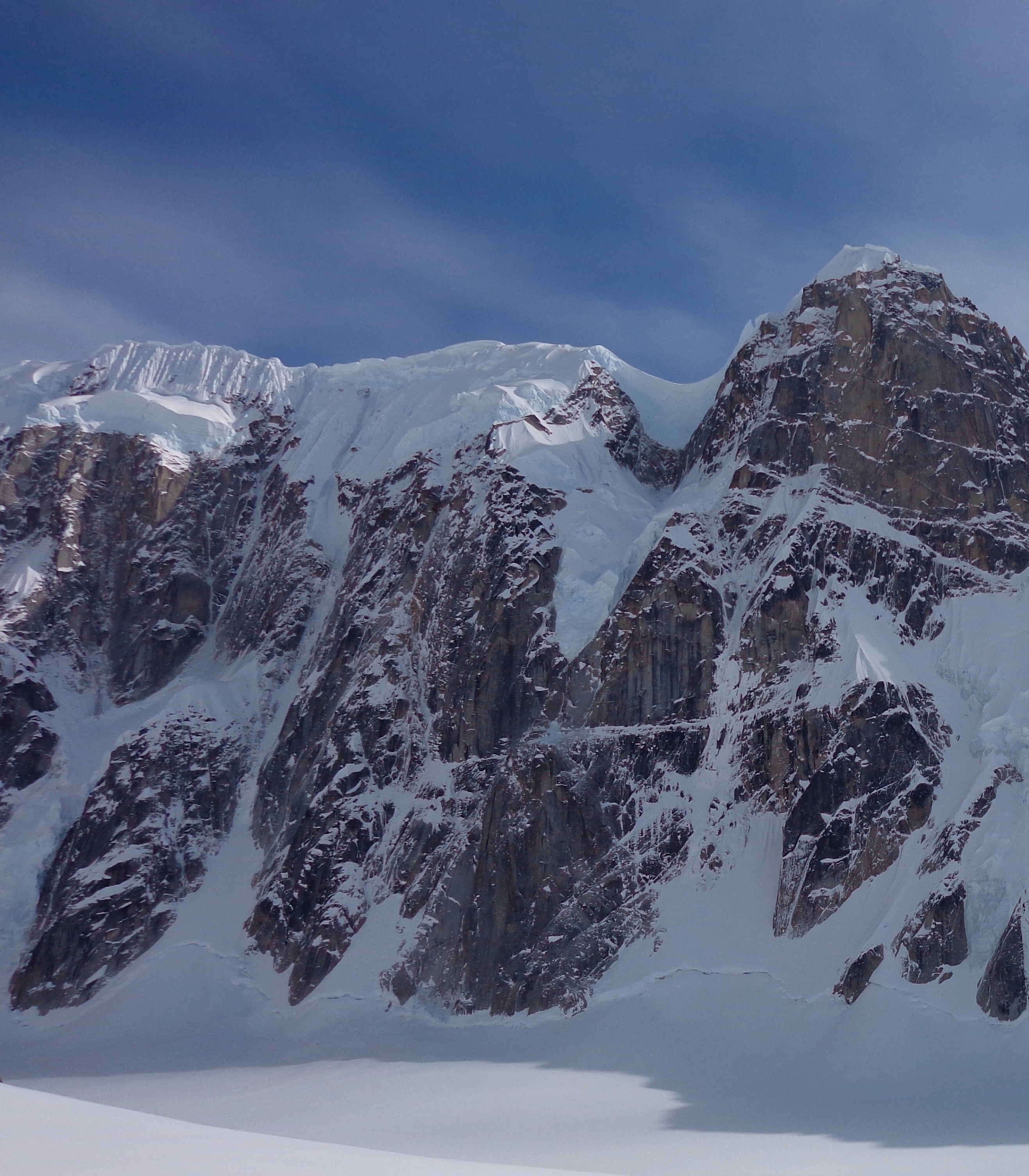 a steep, snow-covered ridge overlooking a large glacier