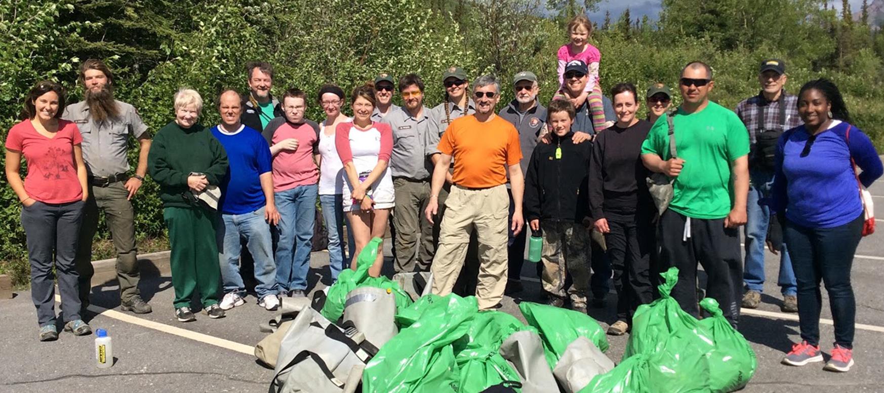 people posing in a group photo next to full trash bags