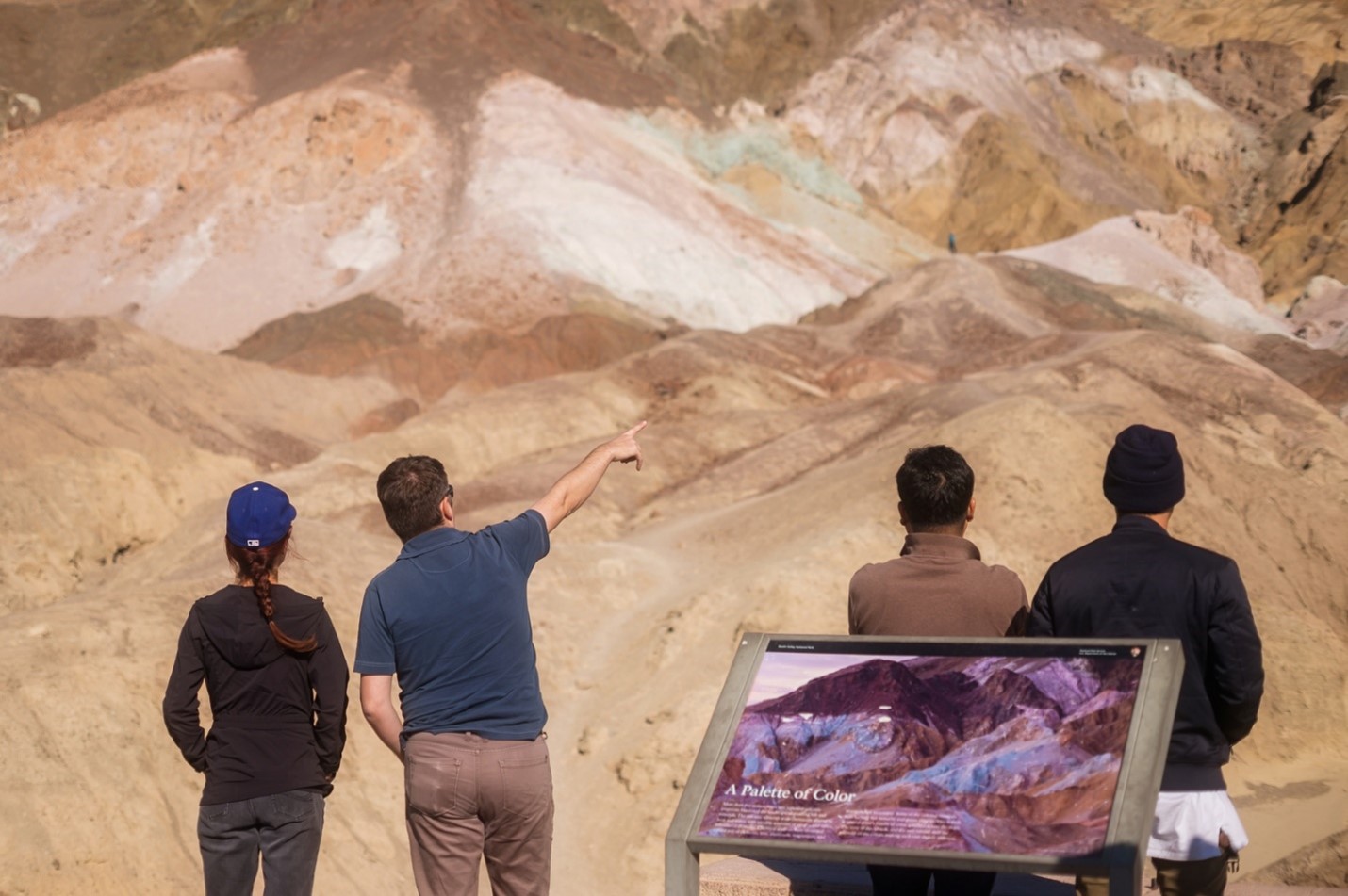 people viewing colorful hills, with an informational sign