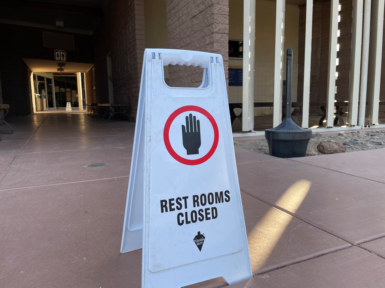 A white temporary A-frame sign shows a hand in a red circle and reads, "Restrooms closed".